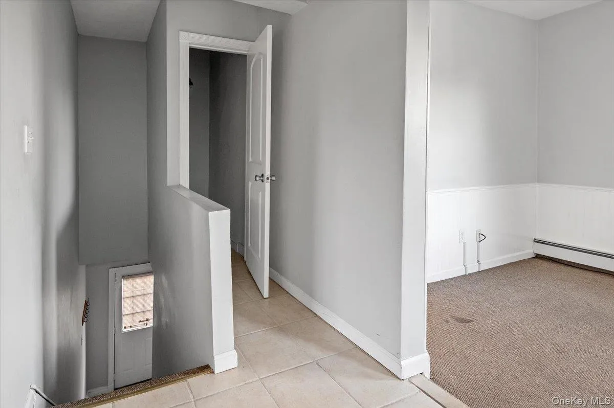 Corridor with light colored carpet, light tile patterned flooring, and wainscoting Corridor with light colored carpet, light tile patterned flooring, and wainscoting