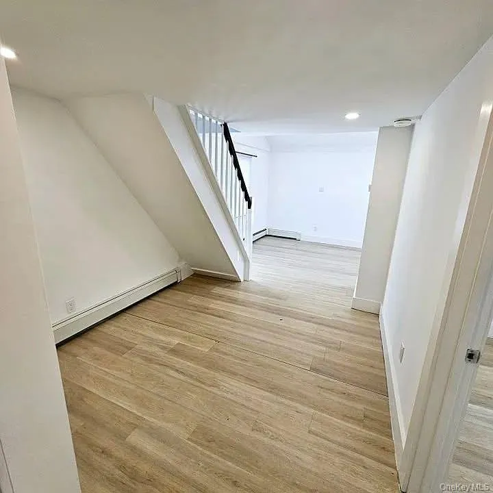 Additional living space featuring light wood-type flooring, a baseboard radiator, stairway, and recessed lighting Additional living space featuring light wood-type flooring, a baseboard radiator, stairway, and recessed lighting