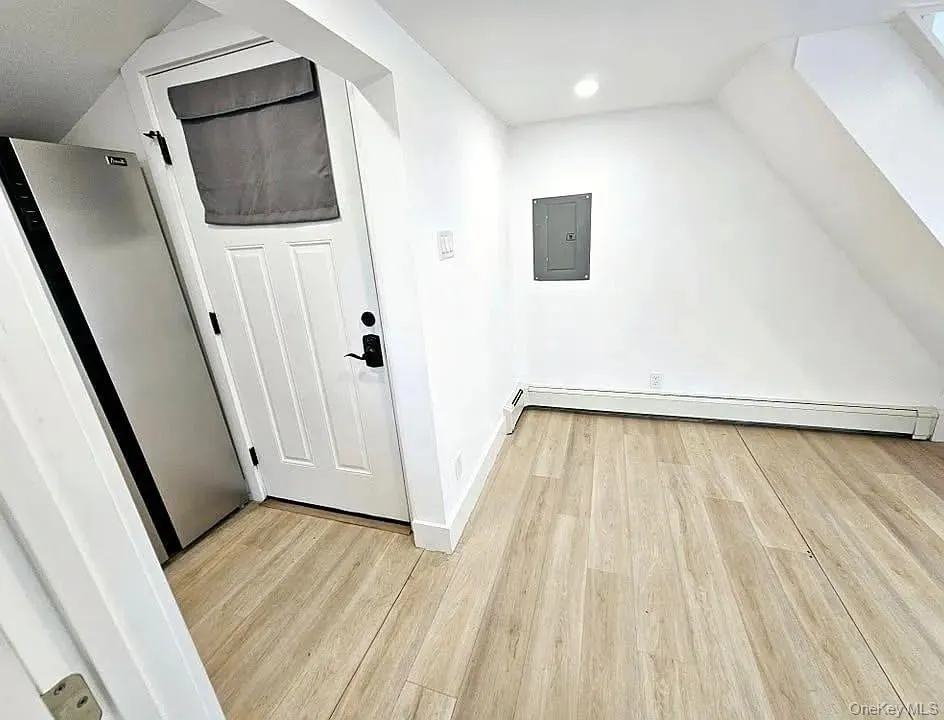 Bonus room featuring light wood-style floors, electric panel, baseboard heating, a skylight, and vaulted ceiling Bonus room featuring light wood-style floors, electric panel, baseboard heating, a skylight, and vaulted ceiling