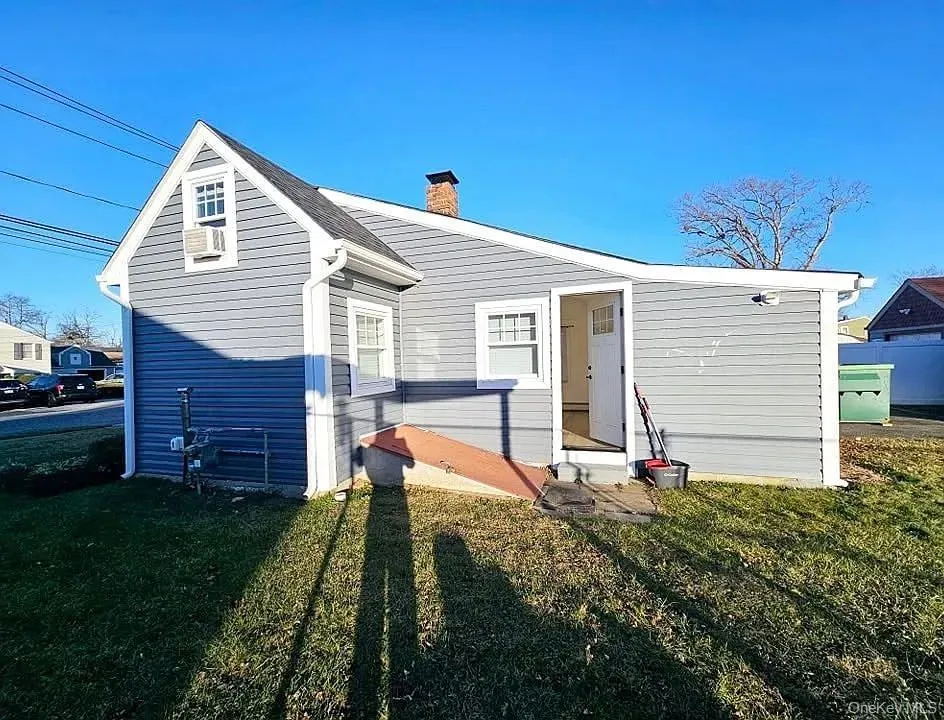 Rear view of house with a lawn and a chimney Rear view of house with a lawn and a chimney