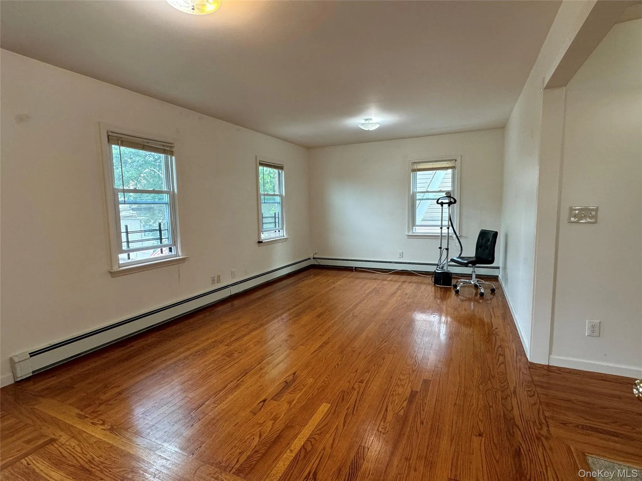 Unfurnished room featuring hardwood / wood-style floors and a baseboard radiator Unfurnished room featuring hardwood / wood-style floors and a baseboard radiator