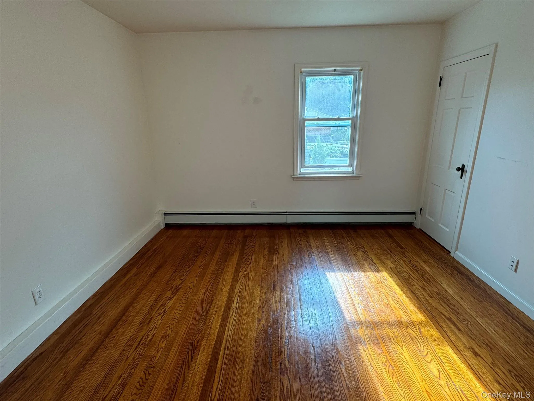 Spare room featuring hardwood / wood-style floors and baseboard heating Spare room featuring hardwood / wood-style floors and baseboard heating