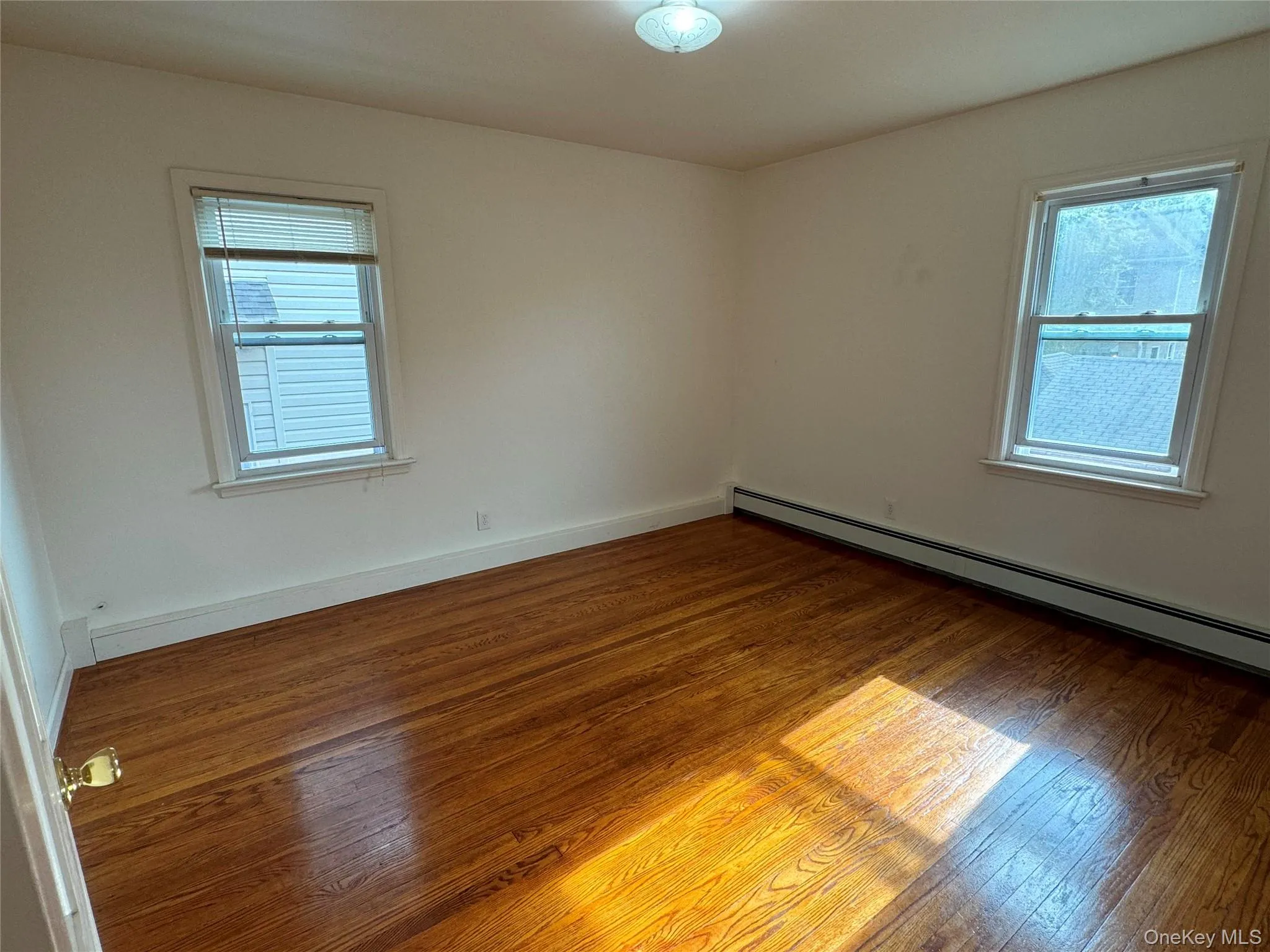 Empty room with wood-type flooring and baseboard heating Empty room with wood-type flooring and baseboard heating