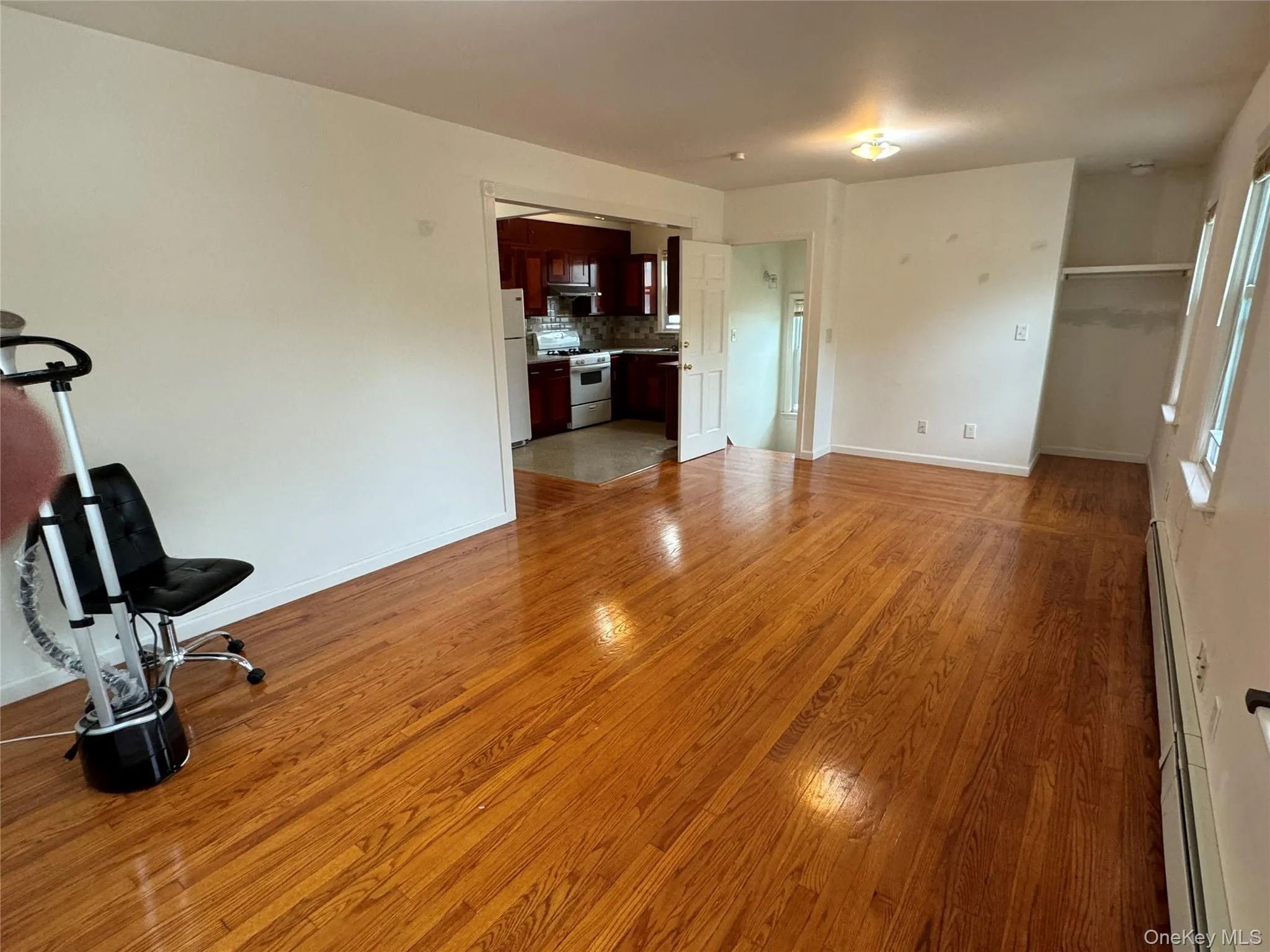 Unfurnished living room featuring light wood finished floors and a baseboard heating unit Unfurnished living room featuring light wood finished floors and a baseboard heating unit