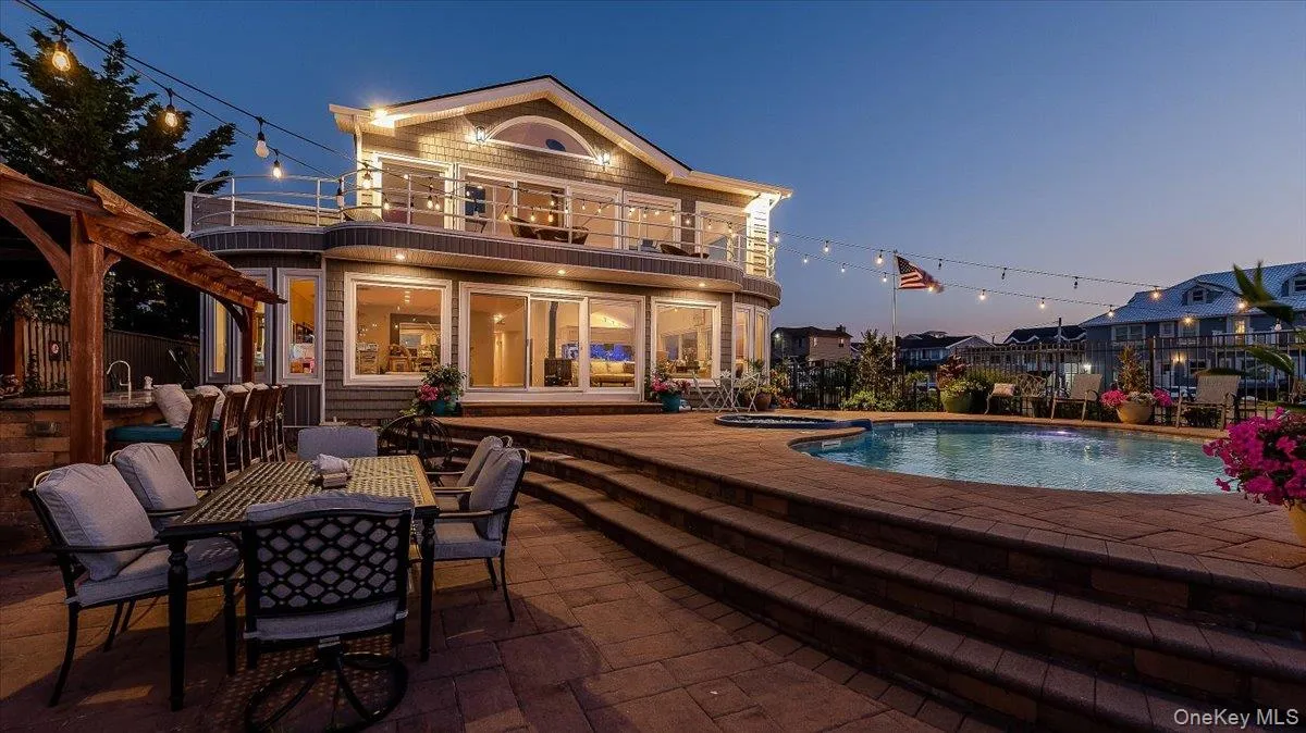 Back of house featuring a patio area, an in-ground hot tub, and outdoor dining area Back of house featuring a patio area, an in-ground hot tub, and outdoor dining area