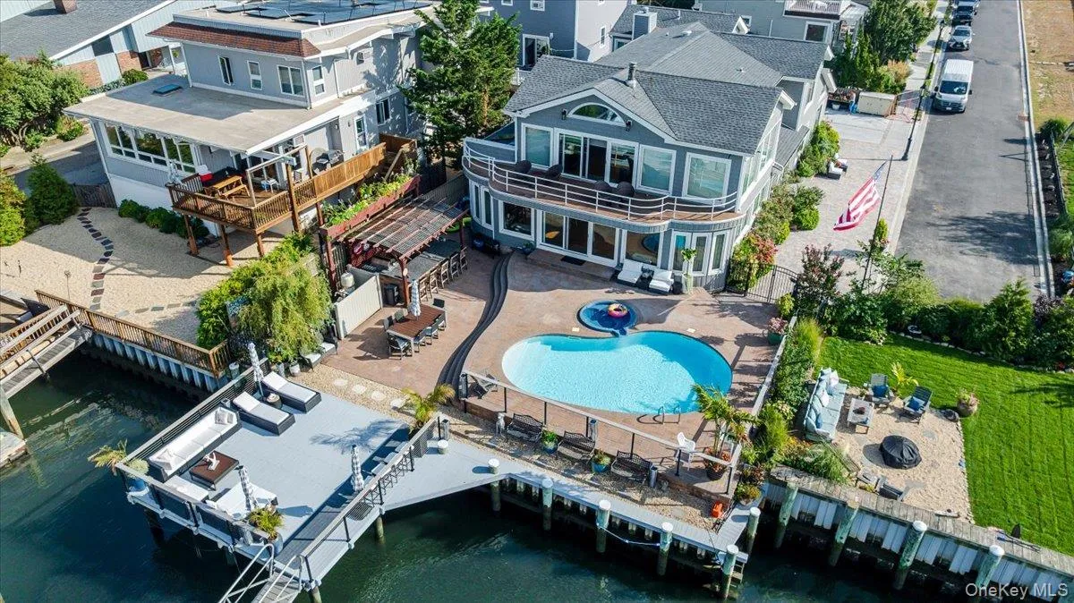 Aerial perspective of suburban area with a pool and a large body of water Aerial perspective of suburban area with a pool and a large body of water