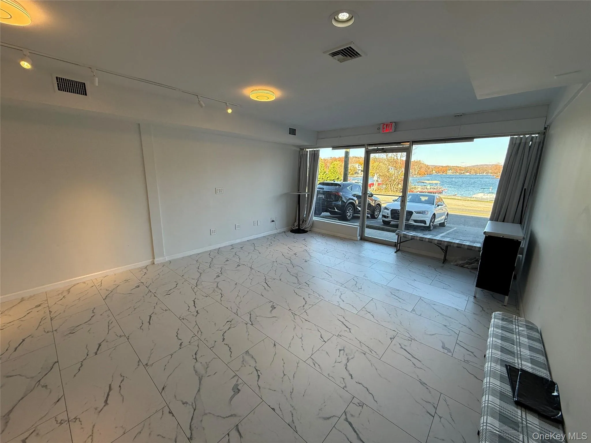Spare room featuring light marble finish flooring, a water view, track lighting, and recessed lighting Spare room featuring light marble finish flooring, a water view, track lighting, and recessed lighting