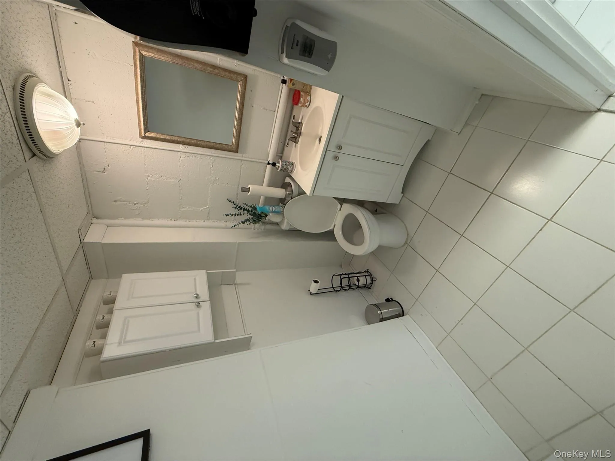 Half bath featuring vanity, a paneled ceiling, light tile patterned floors, and concrete block wall Half bath featuring vanity, a paneled ceiling, light tile patterned floors, and concrete block wall