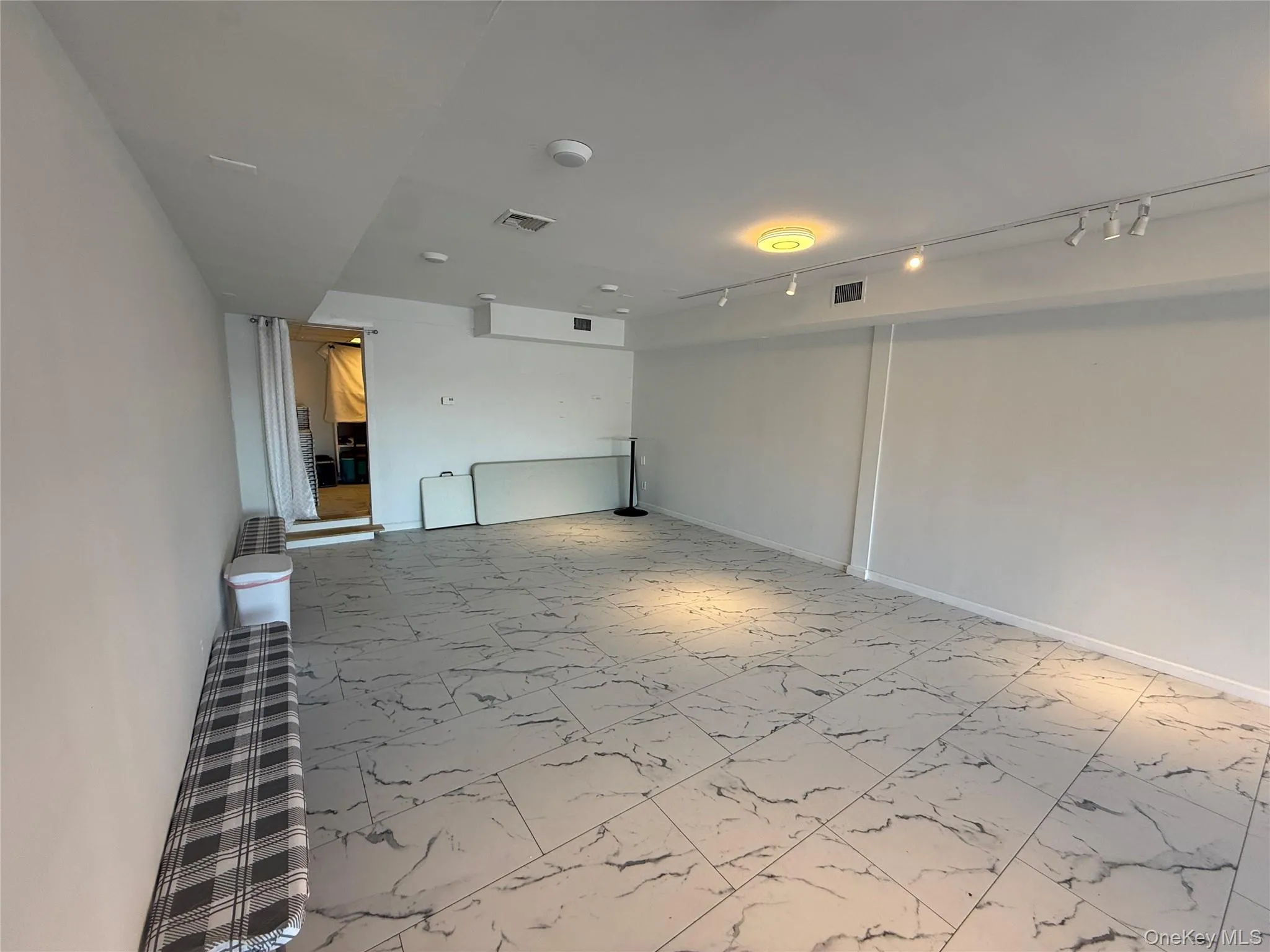 Empty room with light marble finish floors and track lighting Empty room with light marble finish floors and track lighting