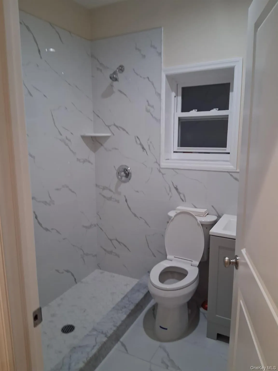 Full bath with vanity, a marble finish shower, and marble finish flooring Full bath with vanity, a marble finish shower, and marble finish flooring