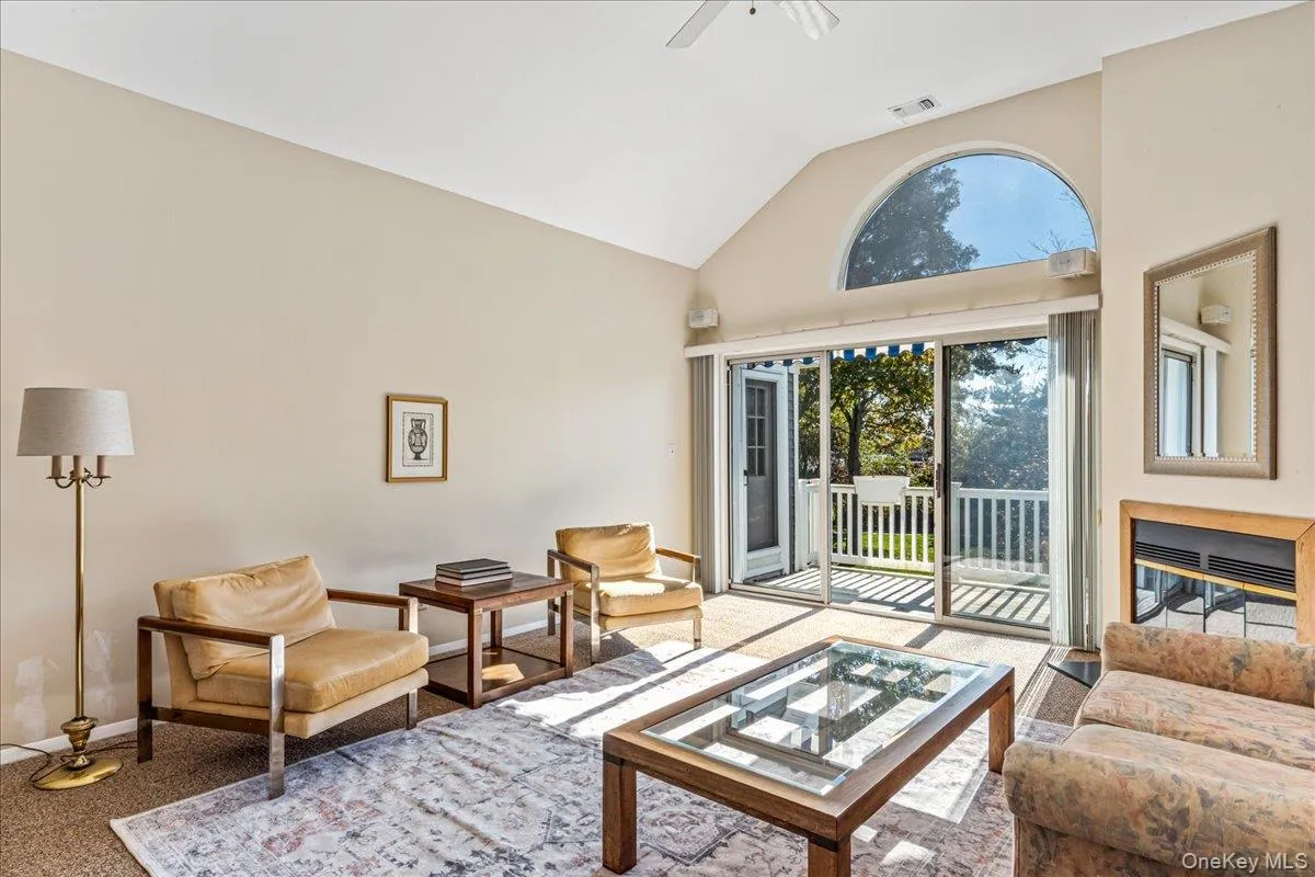 Carpeted living area featuring high vaulted ceiling and ceiling fan Carpeted living area featuring high vaulted ceiling and ceiling fan