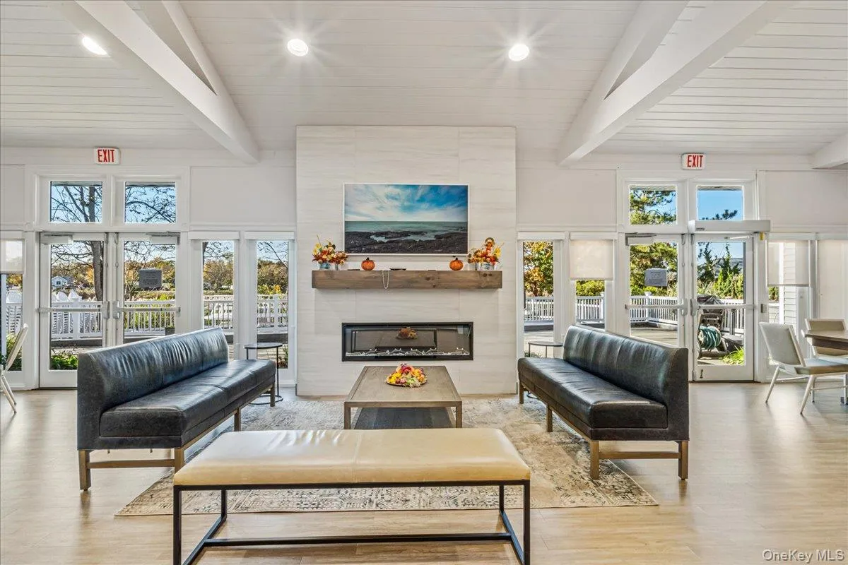 Living room featuring beamed ceiling, wood finished floors, french doors, a fireplace, and high vaulted ceiling Living room featuring beamed ceiling, wood finished floors, french doors, a fireplace, and high vaulted ceiling