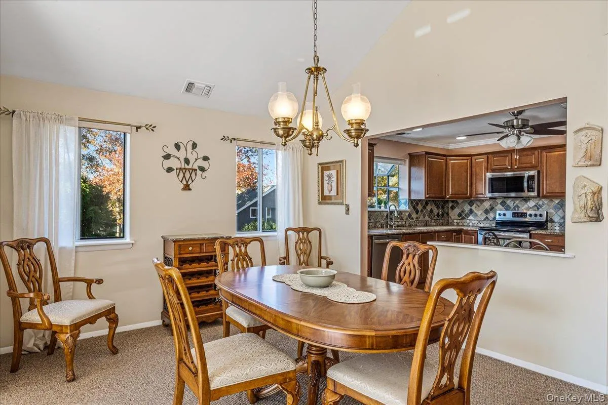 Dining room with a chandelier, light colored carpet, high vaulted ceiling, and a ceiling fan Dining room with a chandelier, light colored carpet, high vaulted ceiling, and a ceiling fan