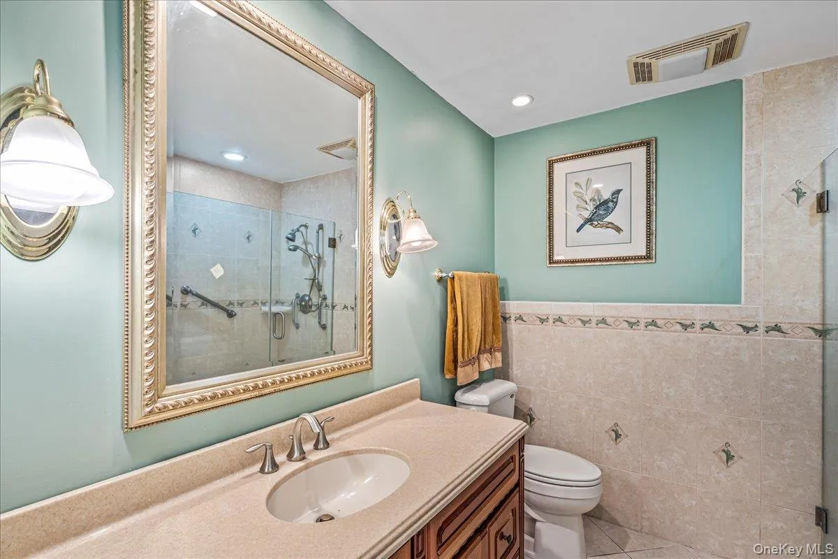 Bathroom with tile walls, a stall shower, vanity, light tile patterned floors, and recessed lighting Bathroom with tile walls, a stall shower, vanity, light tile patterned floors, and recessed lighting
