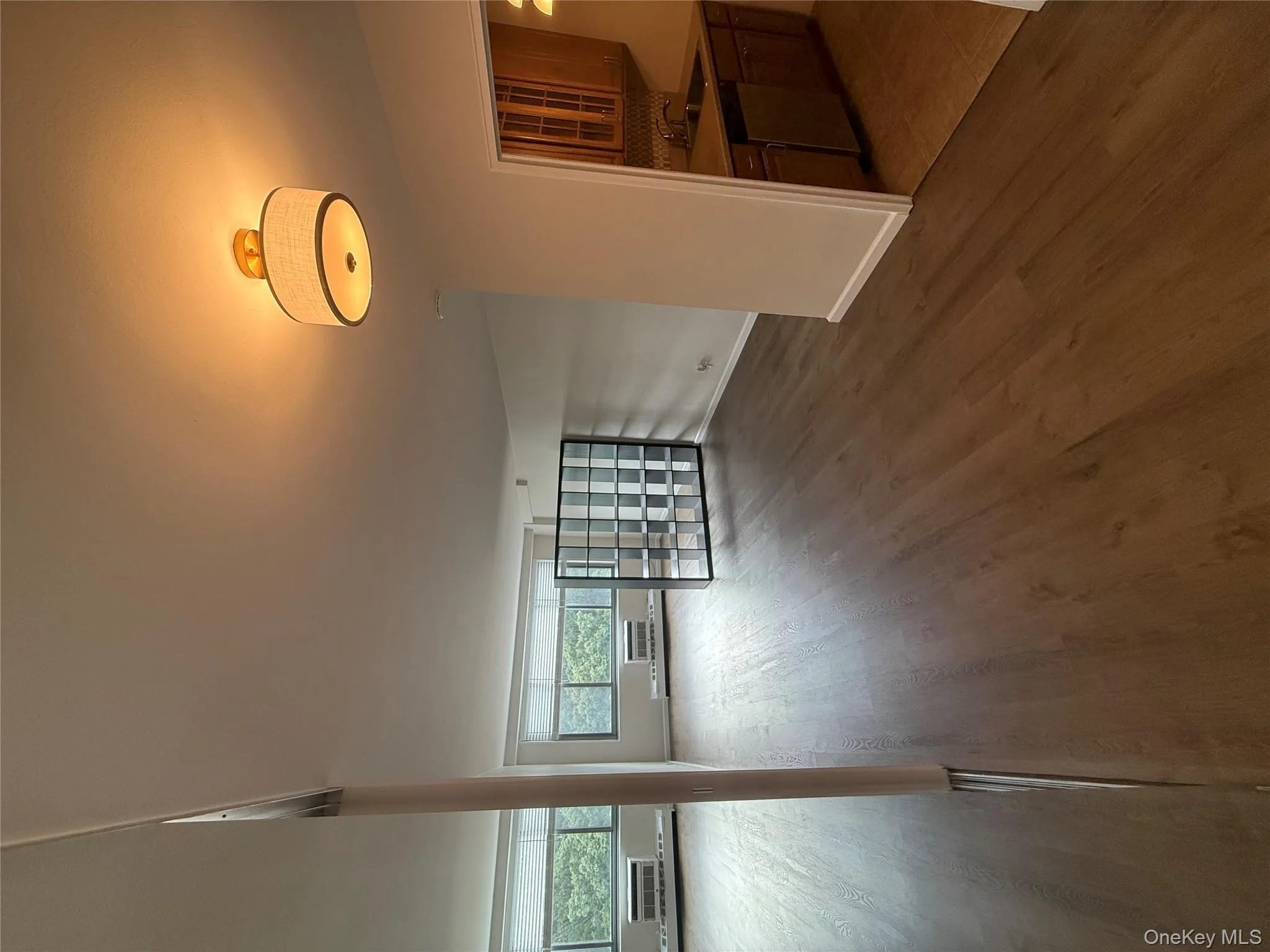 Unfurnished living room featuring dark wood-style floors, baseboard heating, and a wall mounted air conditioner Unfurnished living room featuring dark wood-style floors, baseboard heating, and a wall mounted air conditioner