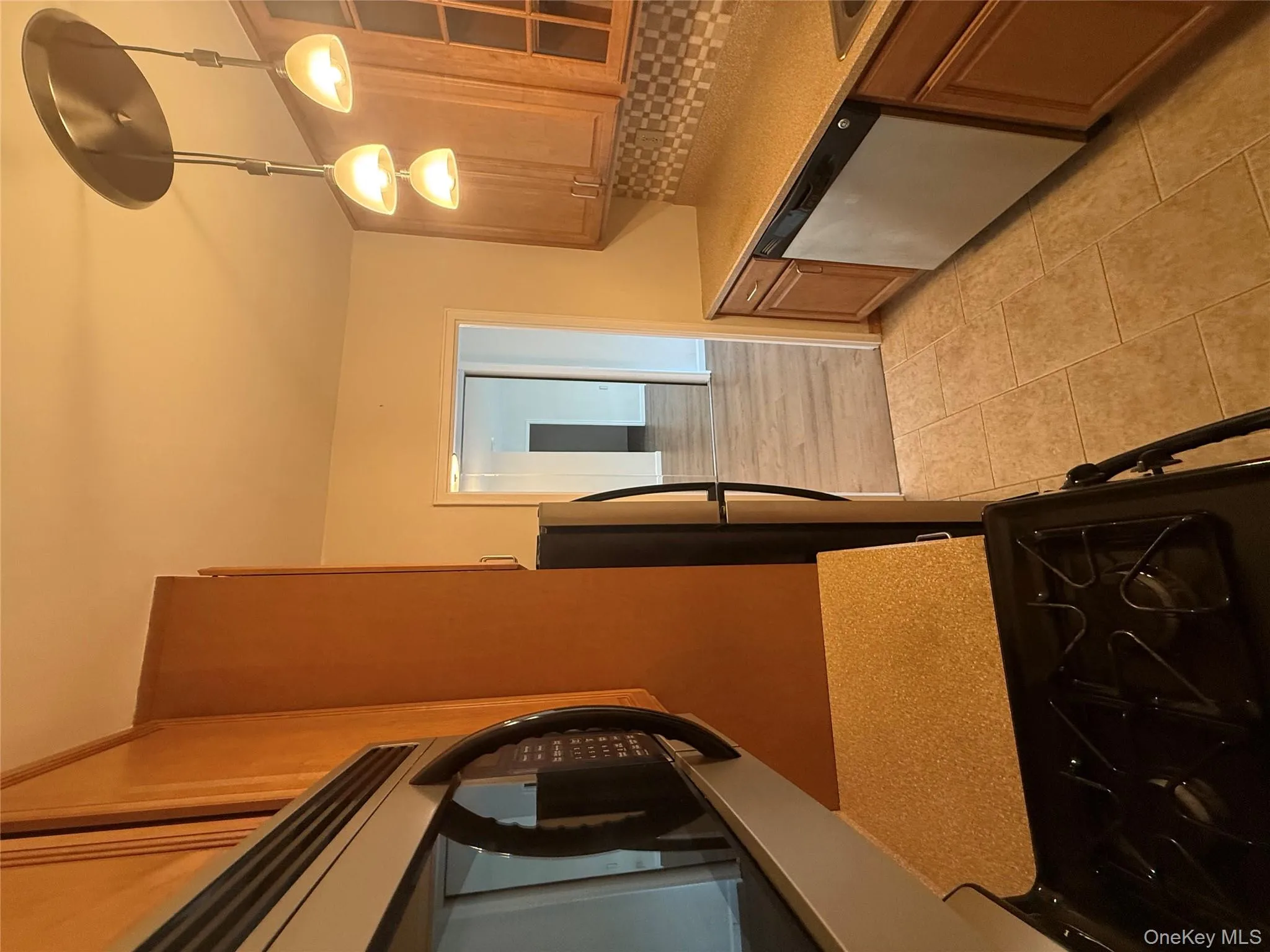 Kitchen featuring backsplash, stainless steel range, dishwashing machine, light tile patterned floors, and light stone counters Kitchen featuring backsplash, stainless steel range, dishwashing machine, light tile patterned floors, and light stone counters