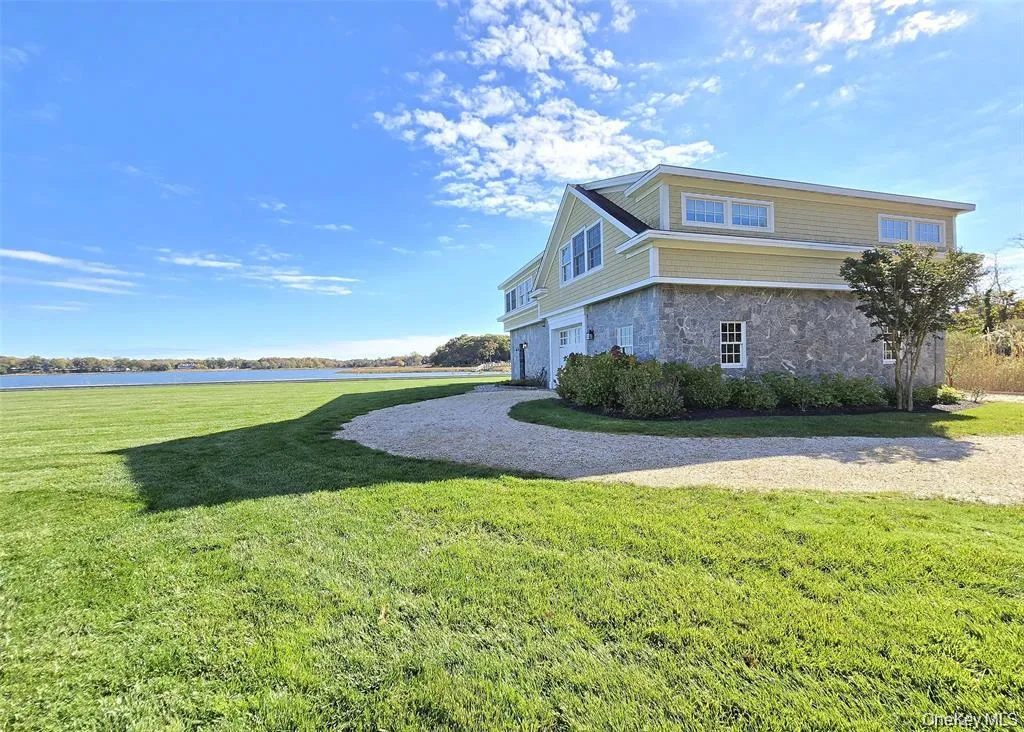 View of side of home with a yard, stone siding, and a water view View of side of home with a yard, stone siding, and a water view