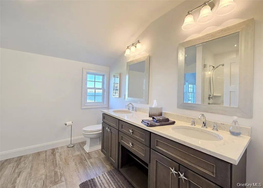 Full bathroom with vaulted ceiling, light wood-style flooring, double vanity, and a shower Full bathroom with vaulted ceiling, light wood-style flooring, double vanity, and a shower