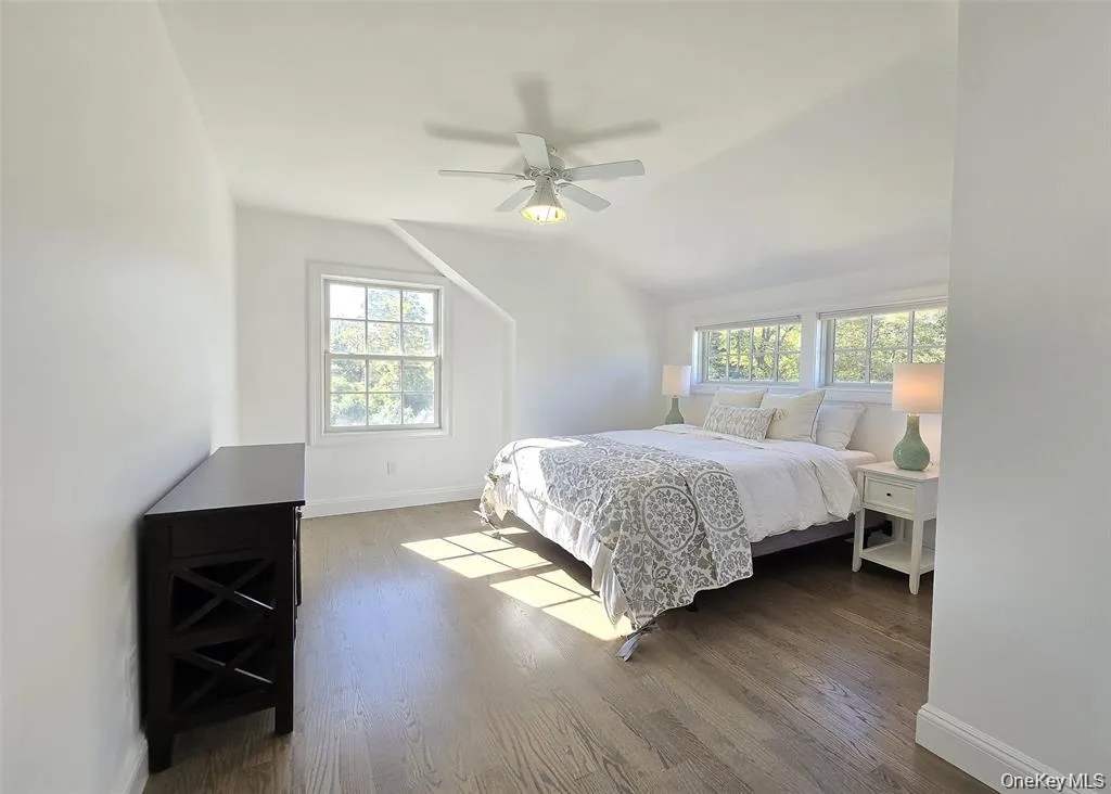 Bedroom with wood finished floors, vaulted ceiling, and a ceiling fan Bedroom with wood finished floors, vaulted ceiling, and a ceiling fan