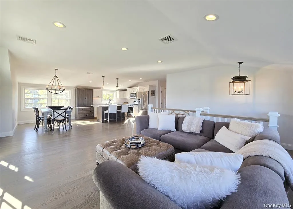 Living room with a chandelier, recessed lighting, light wood-type flooring, and lofted ceiling Living room with a chandelier, recessed lighting, light wood-type flooring, and lofted ceiling