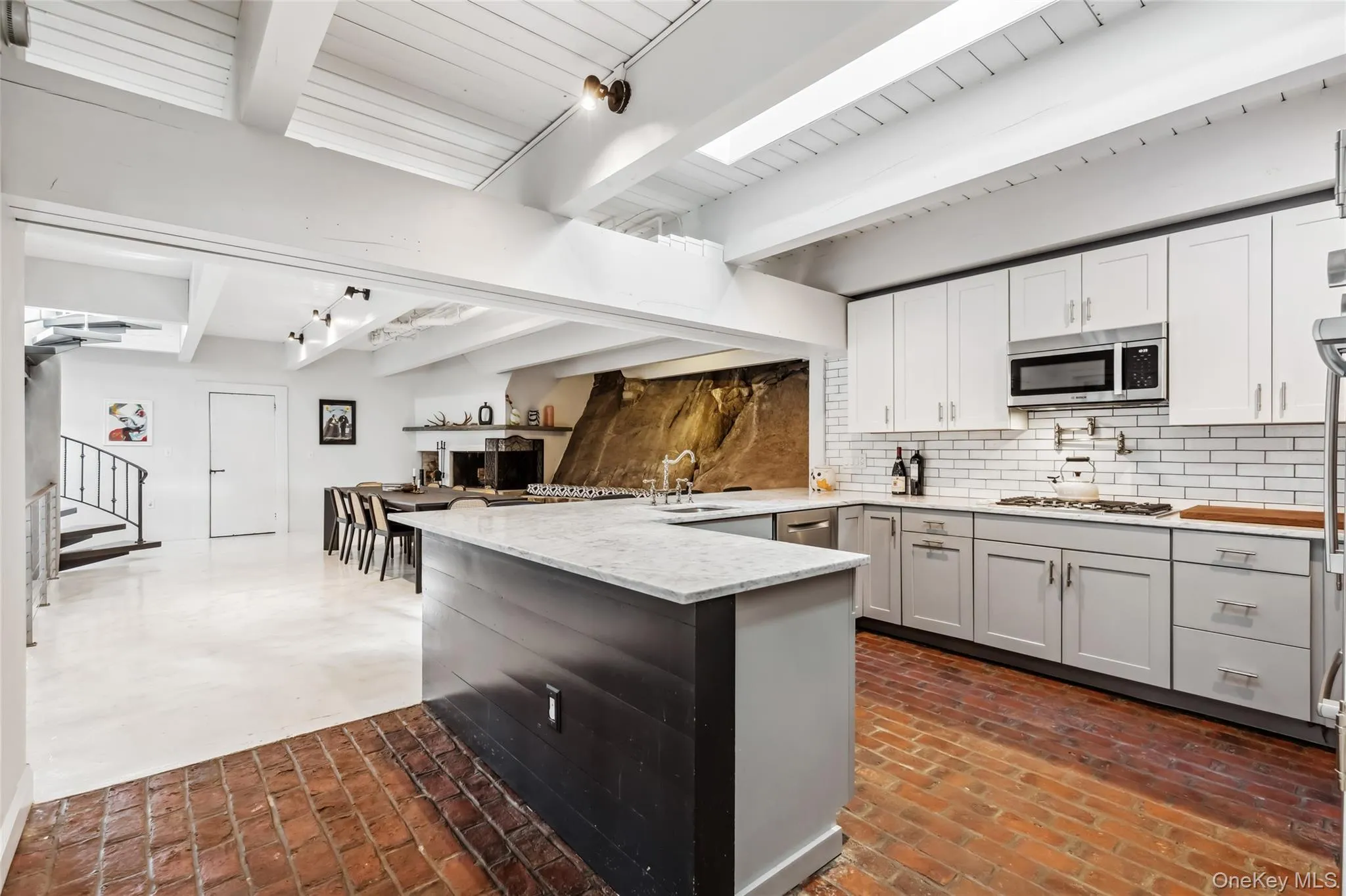 Kitchen featuring kitchen peninsula, tasteful backsplash, white gas stovetop, sink, and beam ceiling Kitchen featuring kitchen peninsula, tasteful backsplash, white gas stovetop, sink, and beam ceiling