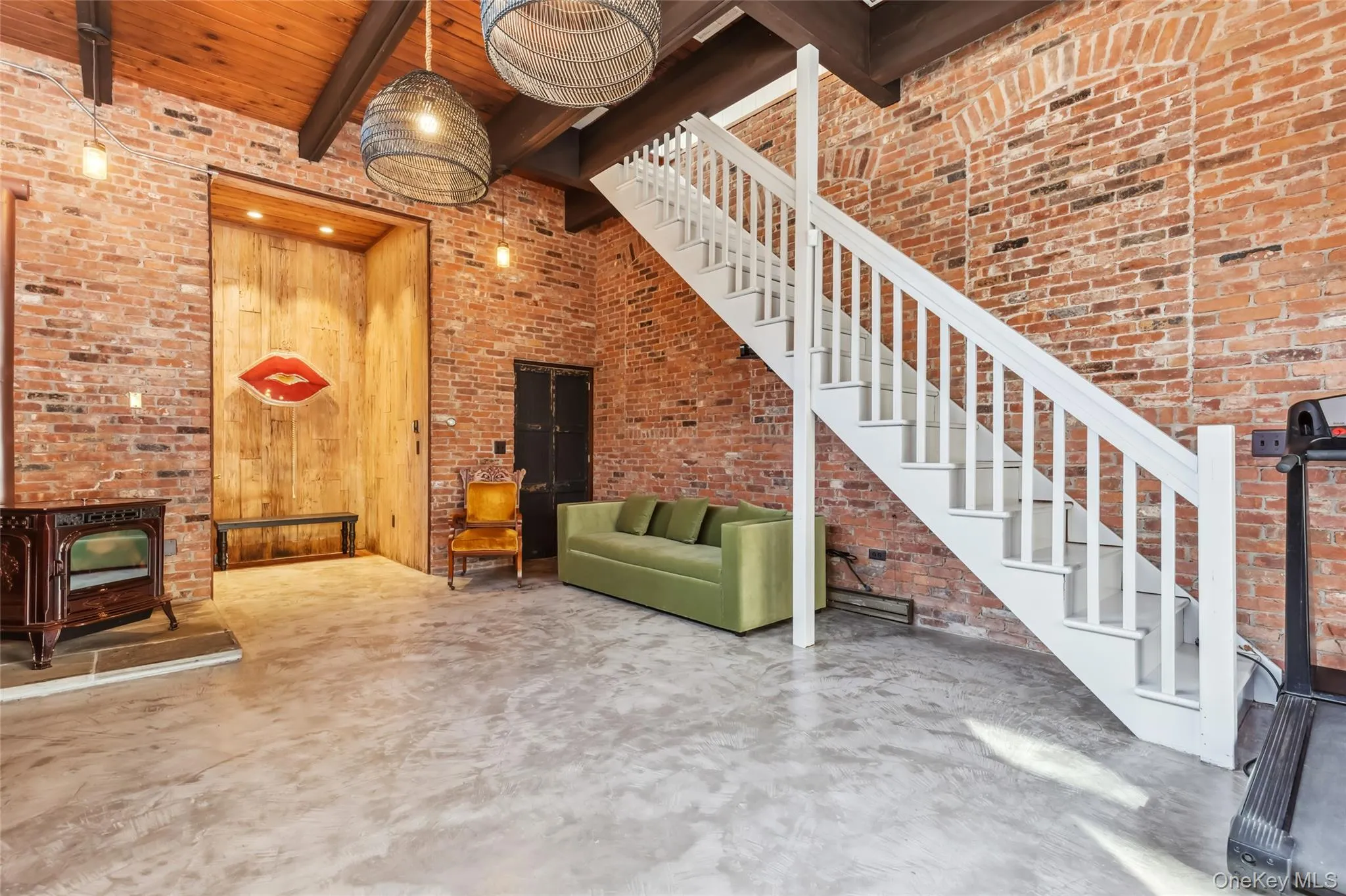 Unfurnished living room/bedroom featuring wooden walls, beam ceiling, a high ceiling, concrete floors, and a pellet stove Unfurnished living room/bedroom featuring wooden walls, beam ceiling, a high ceiling, concrete floors, and a pellet stove