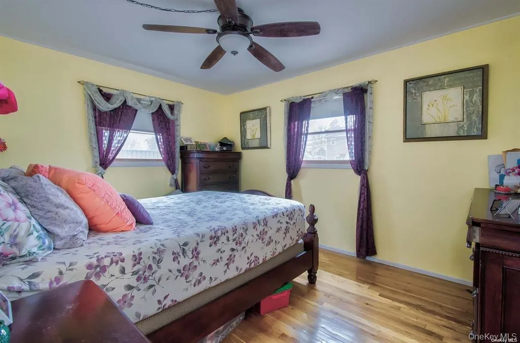 Bedroom featuring wood finished floors, multiple windows, and a ceiling fan Bedroom featuring wood finished floors, multiple windows, and a ceiling fan