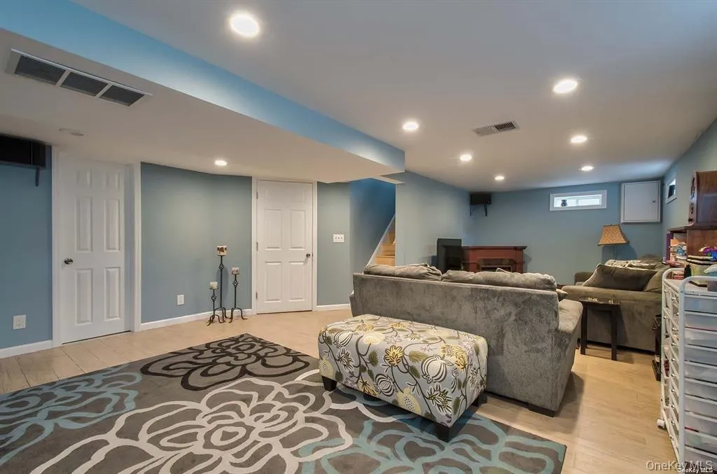 Living room featuring light wood-style floors, recessed lighting, and stairs Living room featuring light wood-style floors, recessed lighting, and stairs