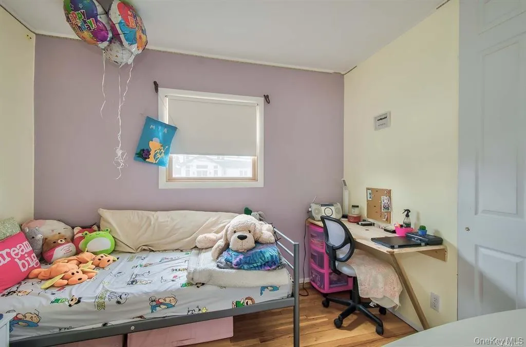 Bedroom with wood finished floors and an office area Bedroom with wood finished floors and an office area