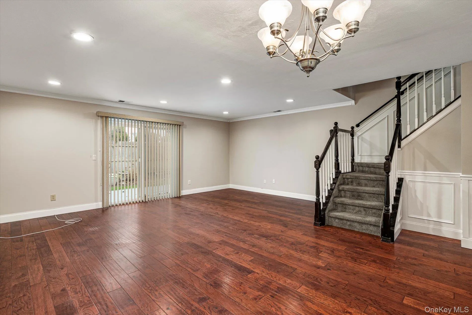 Unfurnished living room featuring dark wood-style floors, a chandelier, stairway, recessed lighting, and ornamental molding Unfurnished living room featuring dark wood-style floors, a chandelier, stairway, recessed lighting, and ornamental molding