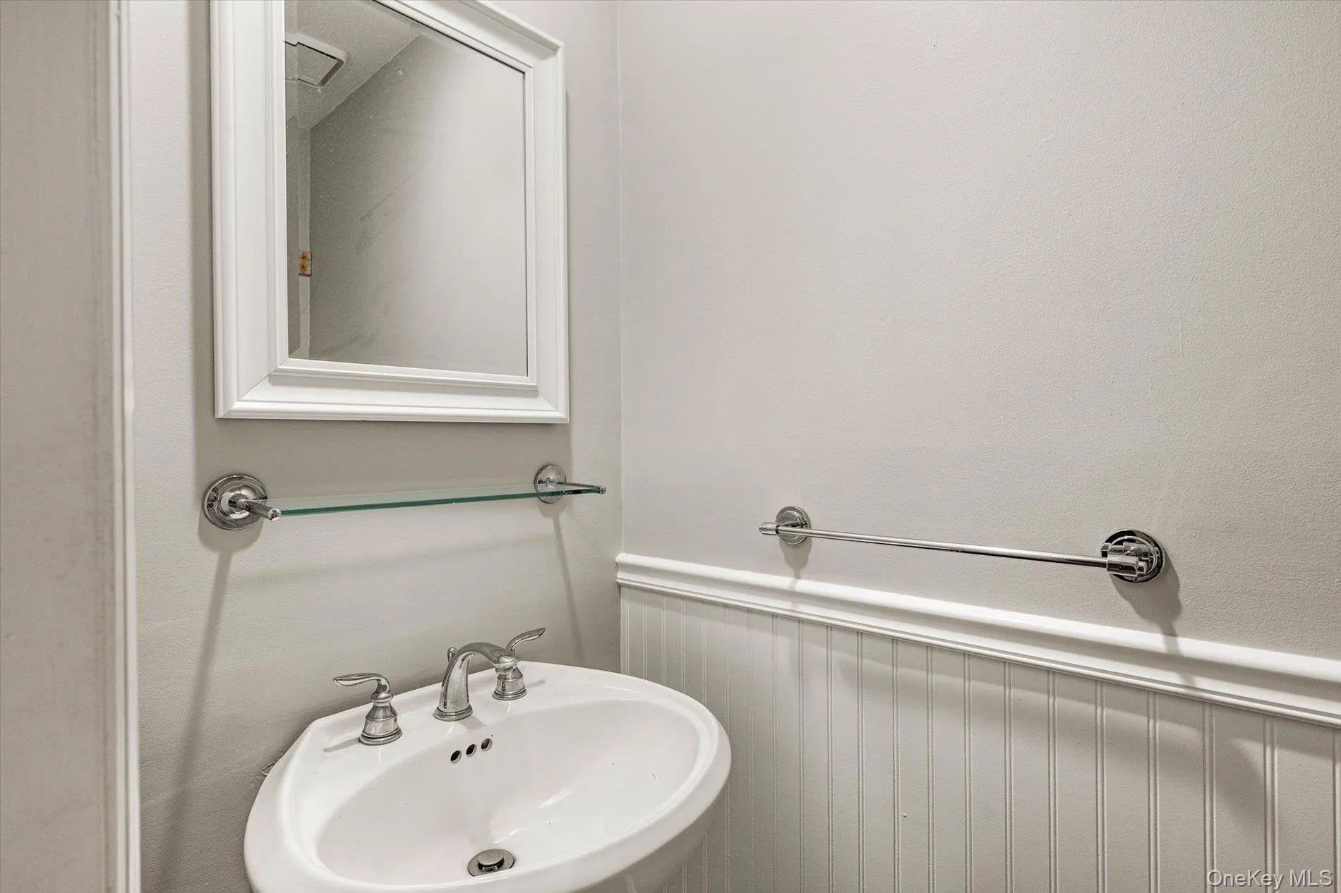 Bathroom featuring a wainscoted wall and a sink Bathroom featuring a wainscoted wall and a sink