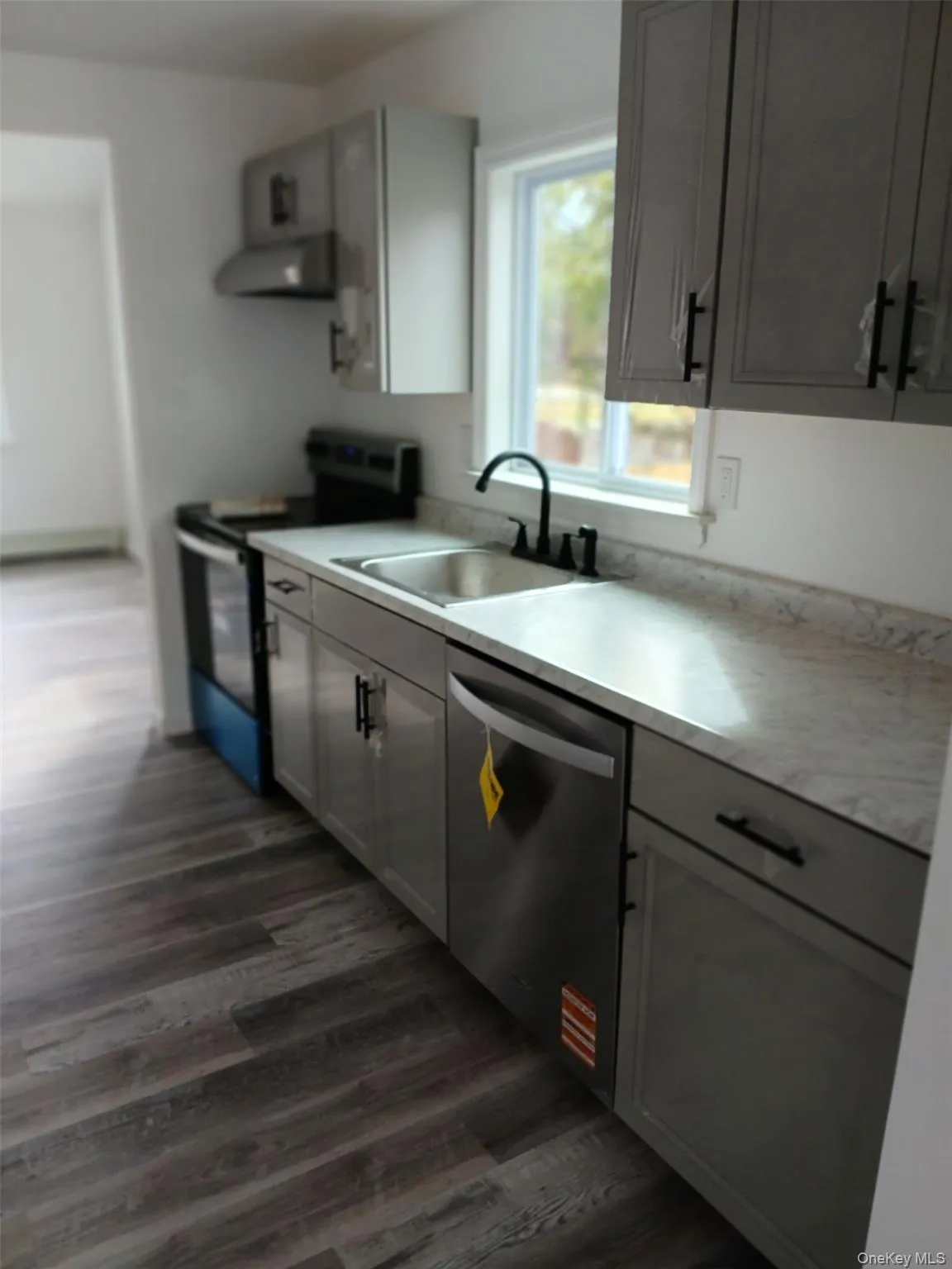 Kitchen featuring light countertops, stainless steel appliances, gray cabinets, and dark wood-type flooring Kitchen featuring light countertops, stainless steel appliances, gray cabinets, and dark wood-type flooring