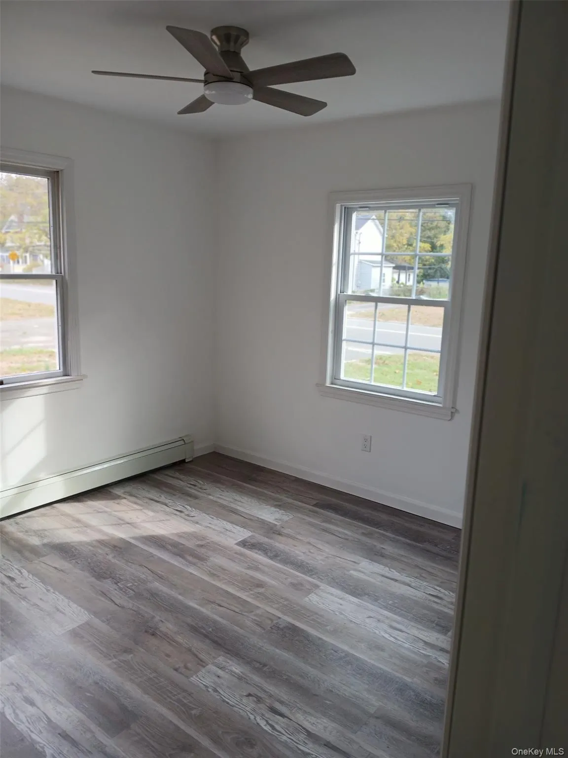 Empty room with a baseboard radiator, light wood-style floors, and ceiling fan Empty room with a baseboard radiator, light wood-style floors, and ceiling fan