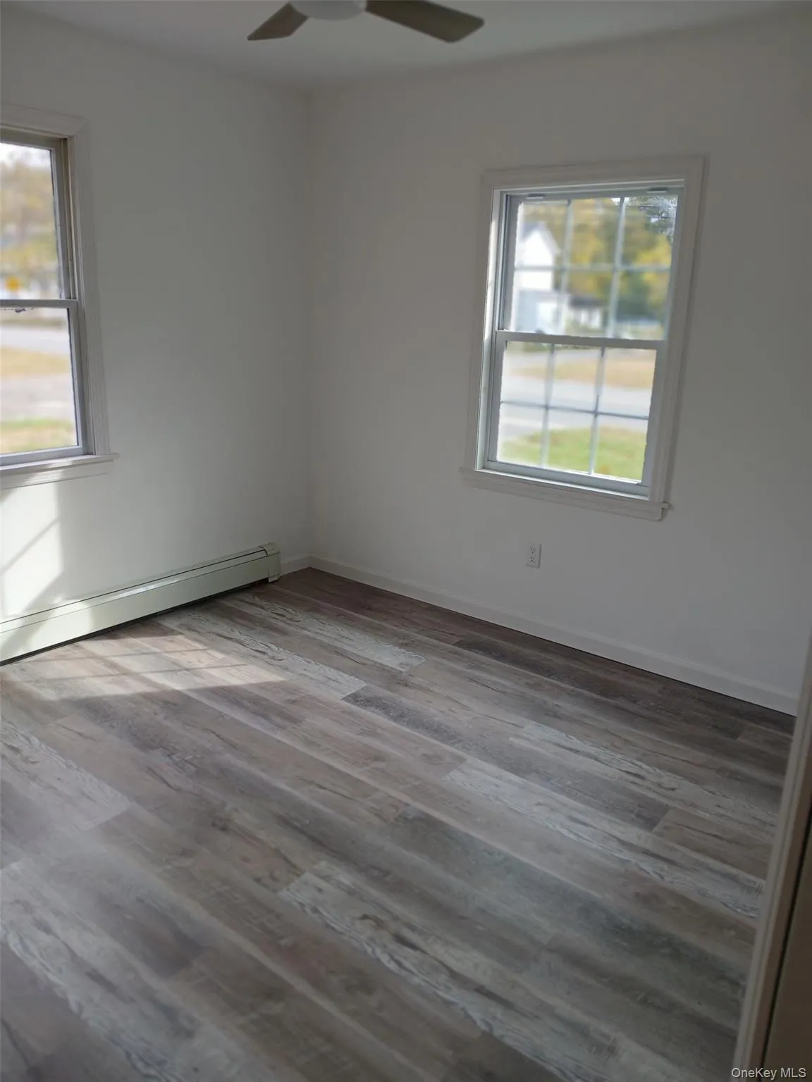 Spare room featuring a baseboard radiator, wood finished floors, and ceiling fan Spare room featuring a baseboard radiator, wood finished floors, and ceiling fan