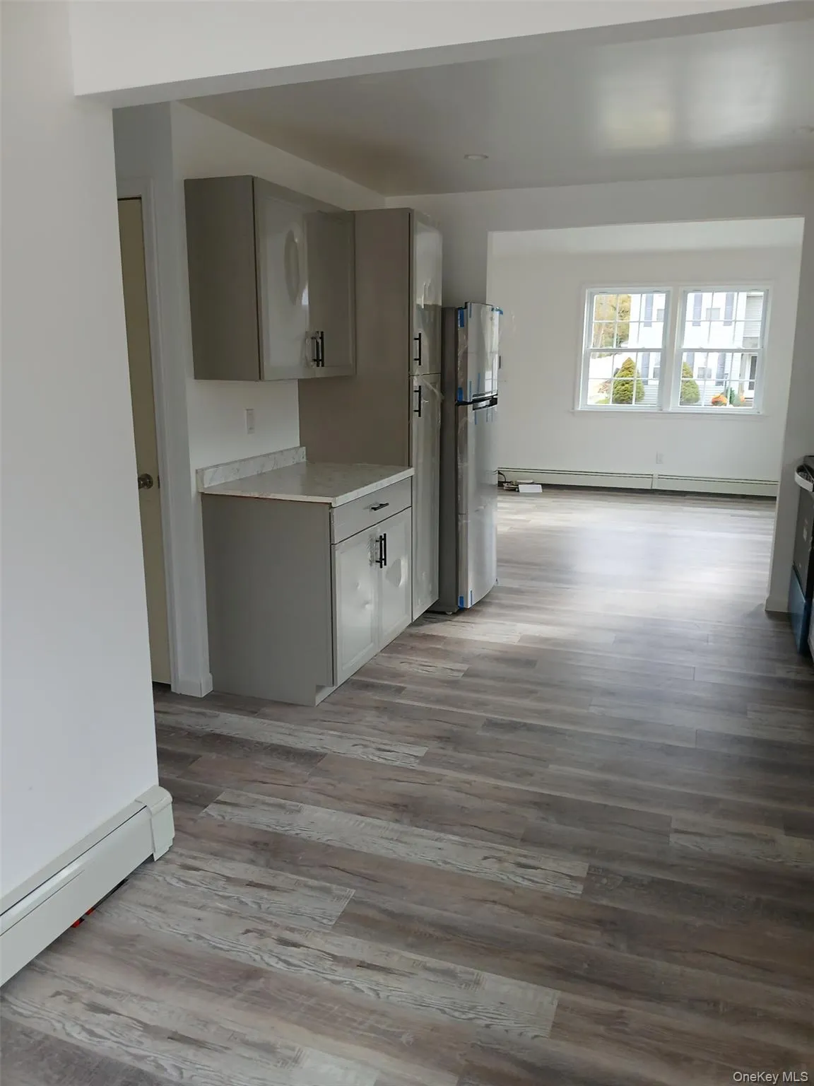 Kitchen featuring light countertops, a baseboard heating unit, freestanding refrigerator, and light wood-style flooring Kitchen featuring light countertops, a baseboard heating unit, freestanding refrigerator, and light wood-style flooring