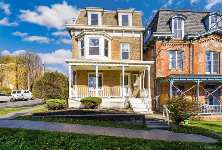 Second empire-style home with a porch, mansard roof, and brick siding