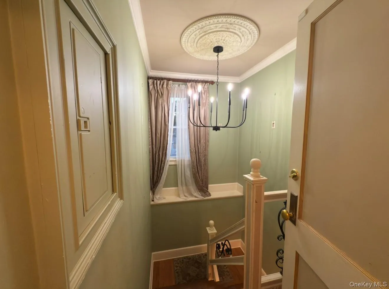 Side entryway with ornamental molding, a chandelier, and wood finished floors Side entryway with ornamental molding, a chandelier, and wood finished floors