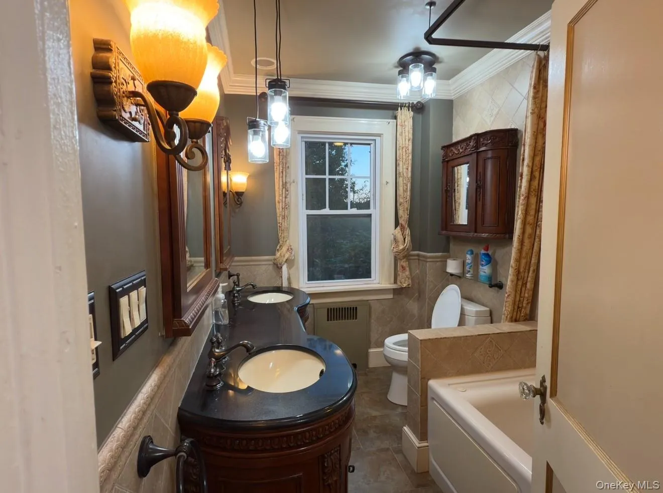 Bathroom featuring a tub to relax in, ornamental molding, radiator, double vanity, and tile walls Bathroom featuring a tub to relax in, ornamental molding, radiator, double vanity, and tile walls