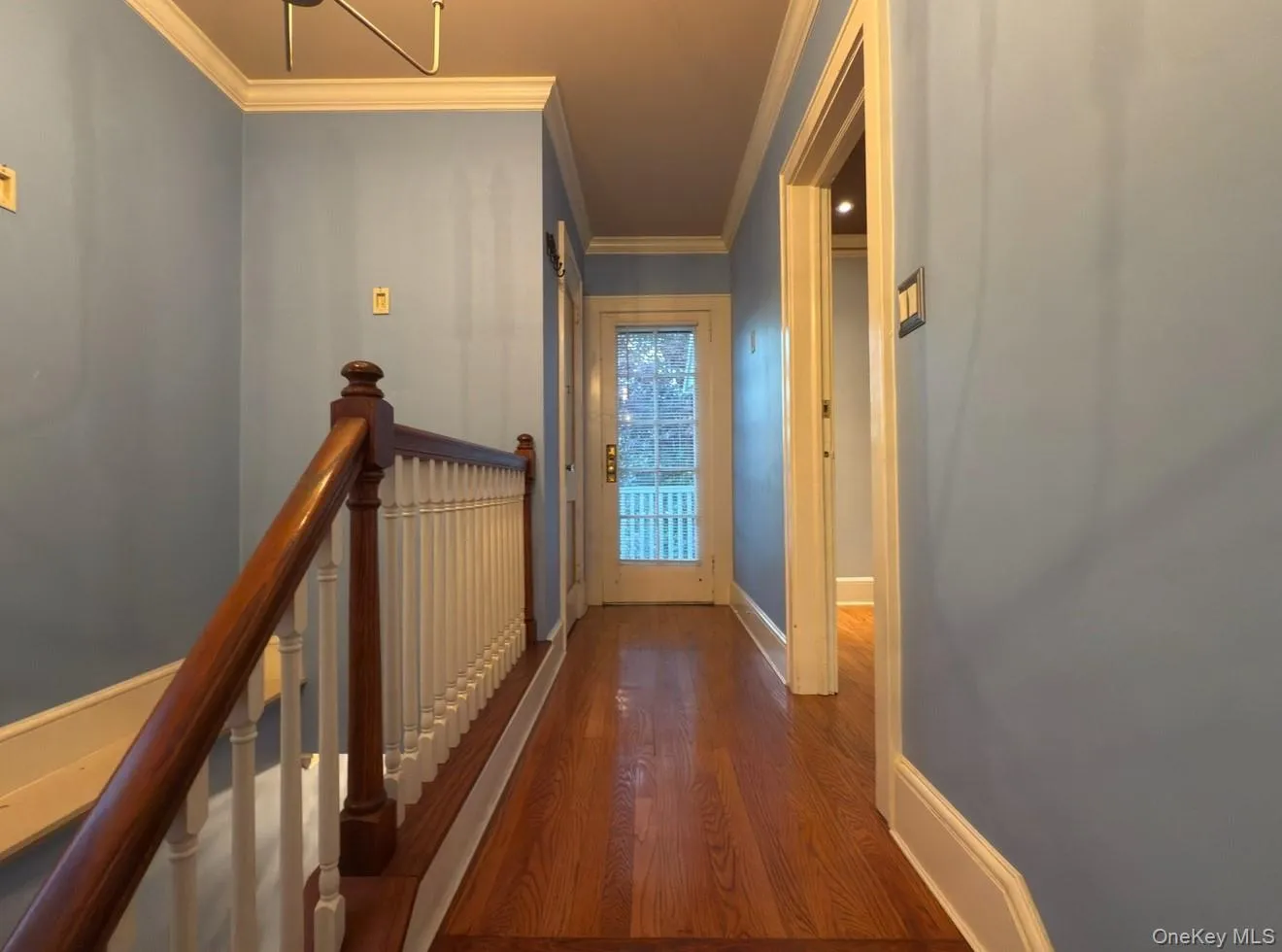 Hall- door to balcony featuring dark wood finished floors, an upstairs landing, and ornamental molding Hall- door to balcony featuring dark wood finished floors, an upstairs landing, and ornamental molding