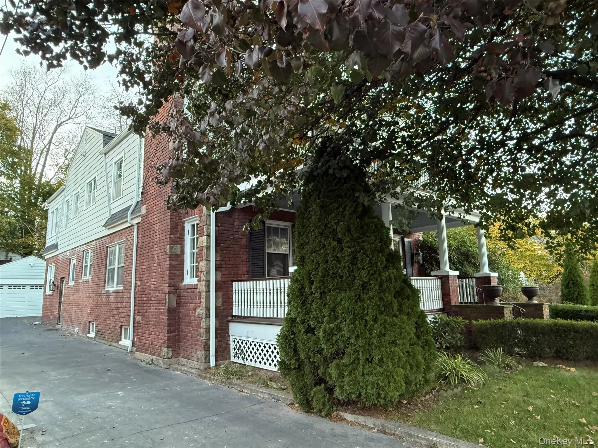 View of side of property with covered porch, an outdoor structure, brick siding, and a detached garage View of side of property with covered porch, an outdoor structure, brick siding, and a detached garage