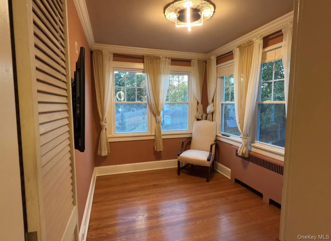 Living area featuring radiator, wood finished floors, and crown molding Living area featuring radiator, wood finished floors, and crown molding