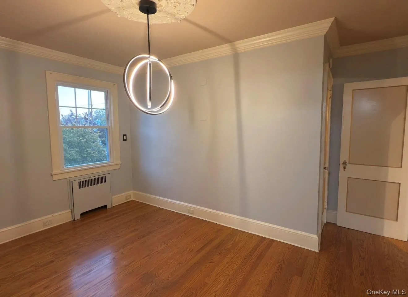 Bedroom 1 with crown molding, radiator, and hardwood flooring Bedroom 1 with crown molding, radiator, and hardwood flooring