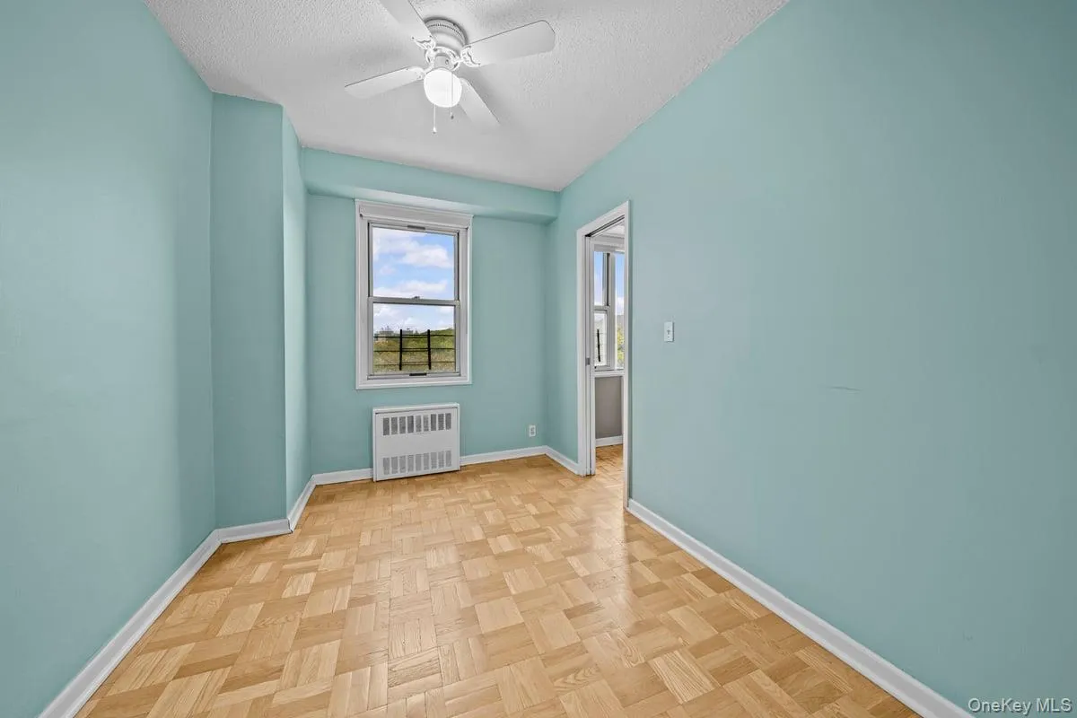 Empty room with radiator heating unit, a textured ceiling, and ceiling fan Empty room with radiator heating unit, a textured ceiling, and ceiling fan