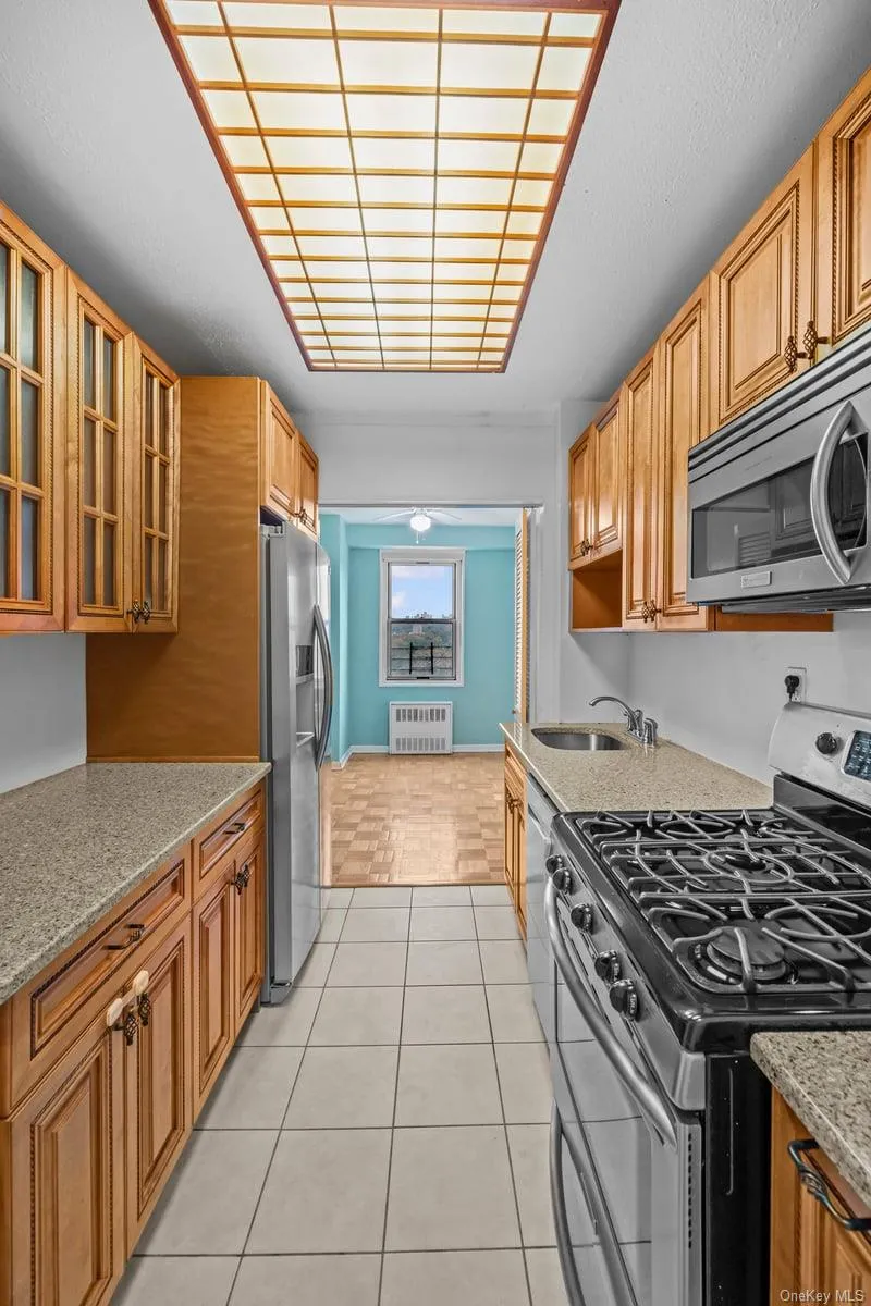 Kitchen with stainless steel appliances, glass insert cabinets, light stone countertops, and light tile patterned floors Kitchen with stainless steel appliances, glass insert cabinets, light stone countertops, and light tile patterned floors