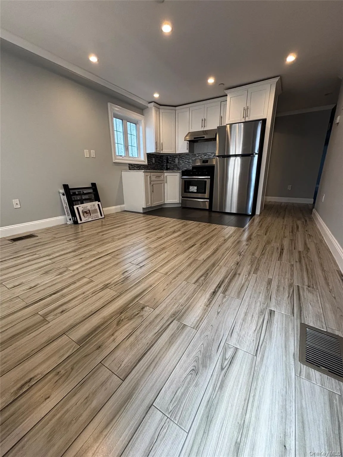 Kitchen featuring white cabinetry, stainless steel appliances, light wood-style flooring, recessed lighting, and backsplash Kitchen featuring white cabinetry, stainless steel appliances, light wood-style flooring, recessed lighting, and backsplash