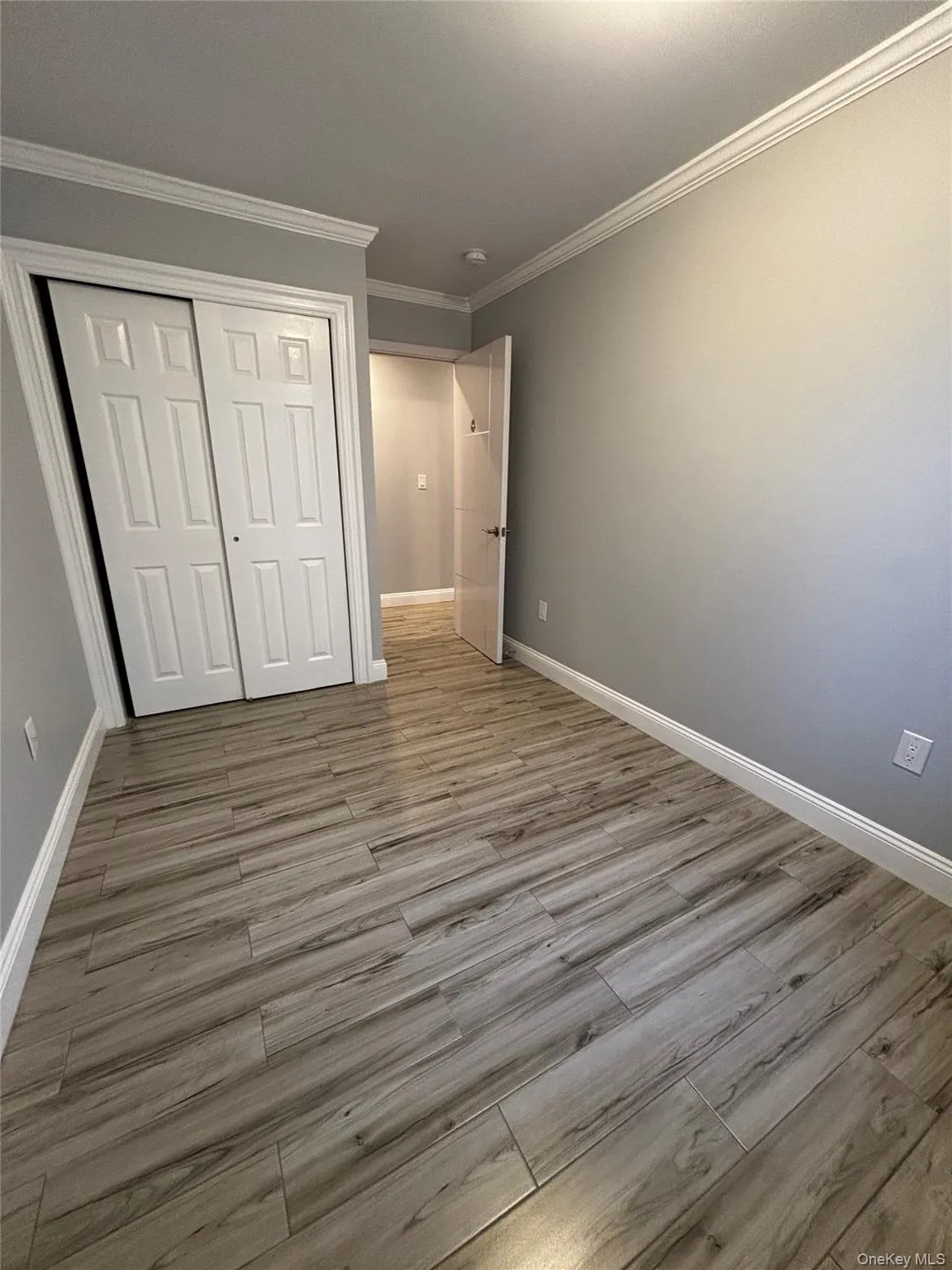 Unfurnished bedroom with ornamental molding, a closet, and light wood-style flooring Unfurnished bedroom with ornamental molding, a closet, and light wood-style flooring
