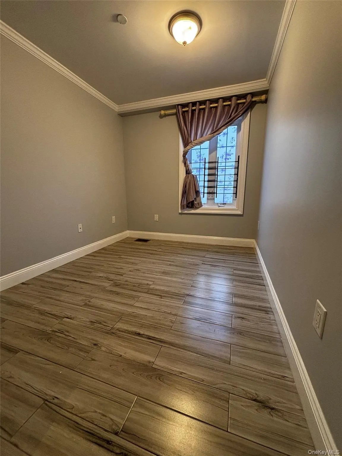 Empty room featuring crown molding and wood finished floors Empty room featuring crown molding and wood finished floors