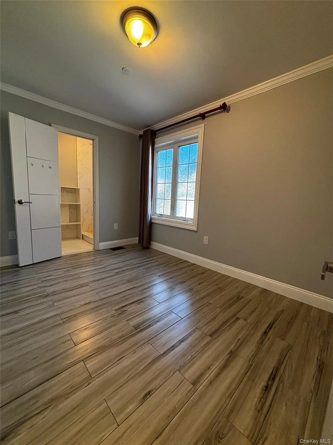 Unfurnished bedroom with crown molding, light wood-style floors, and ensuite bathroom Unfurnished bedroom with crown molding, light wood-style floors, and ensuite bathroom