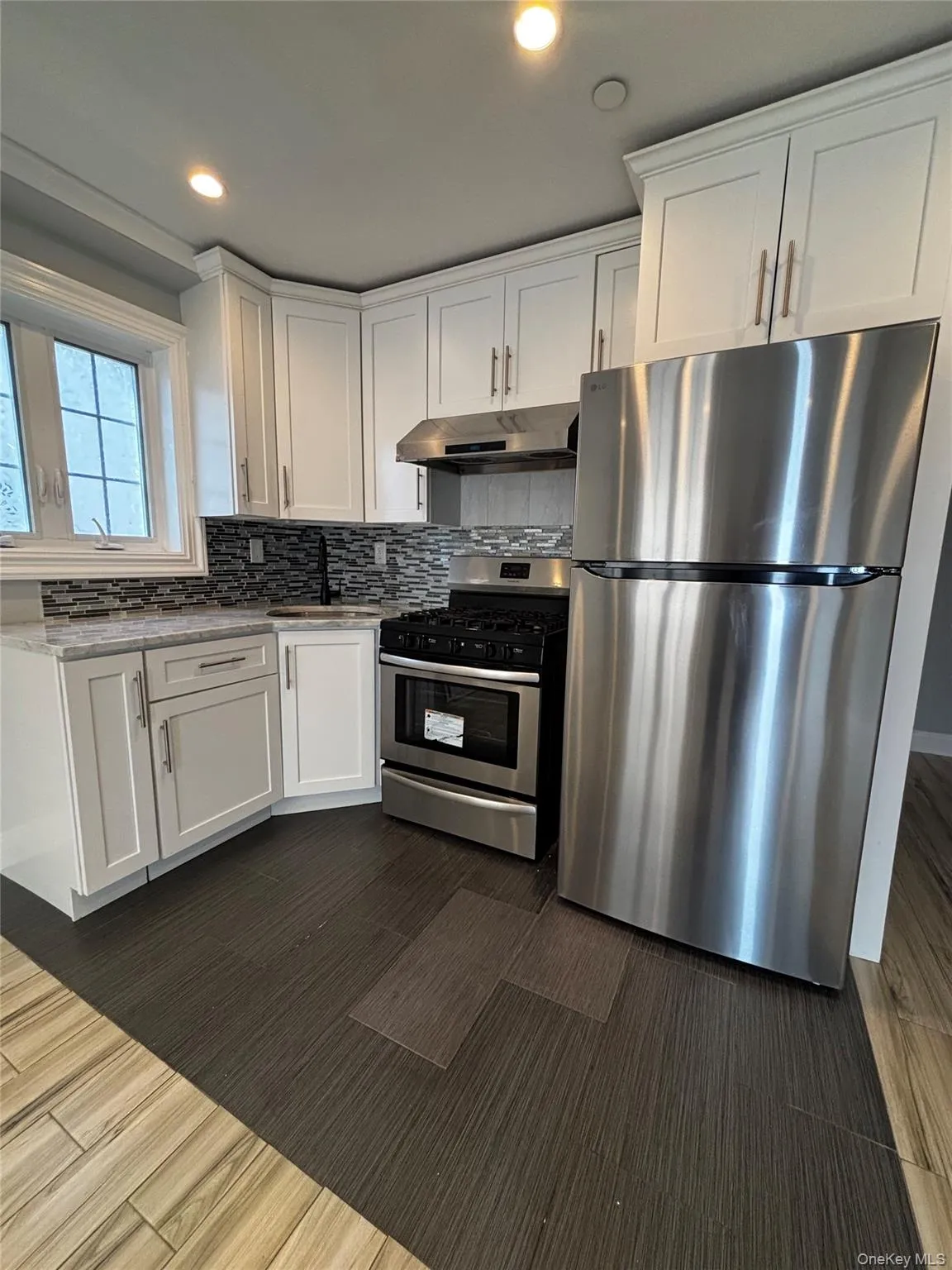 Kitchen featuring appliances with stainless steel finishes, white cabinets, tasteful backsplash, recessed lighting, and dark wood finished floors Kitchen featuring appliances with stainless steel finishes, white cabinets, tasteful backsplash, recessed lighting, and dark wood finished floors