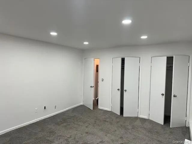 Unfurnished bedroom featuring multiple closets, recessed lighting, and dark colored carpet Unfurnished bedroom featuring multiple closets, recessed lighting, and dark colored carpet